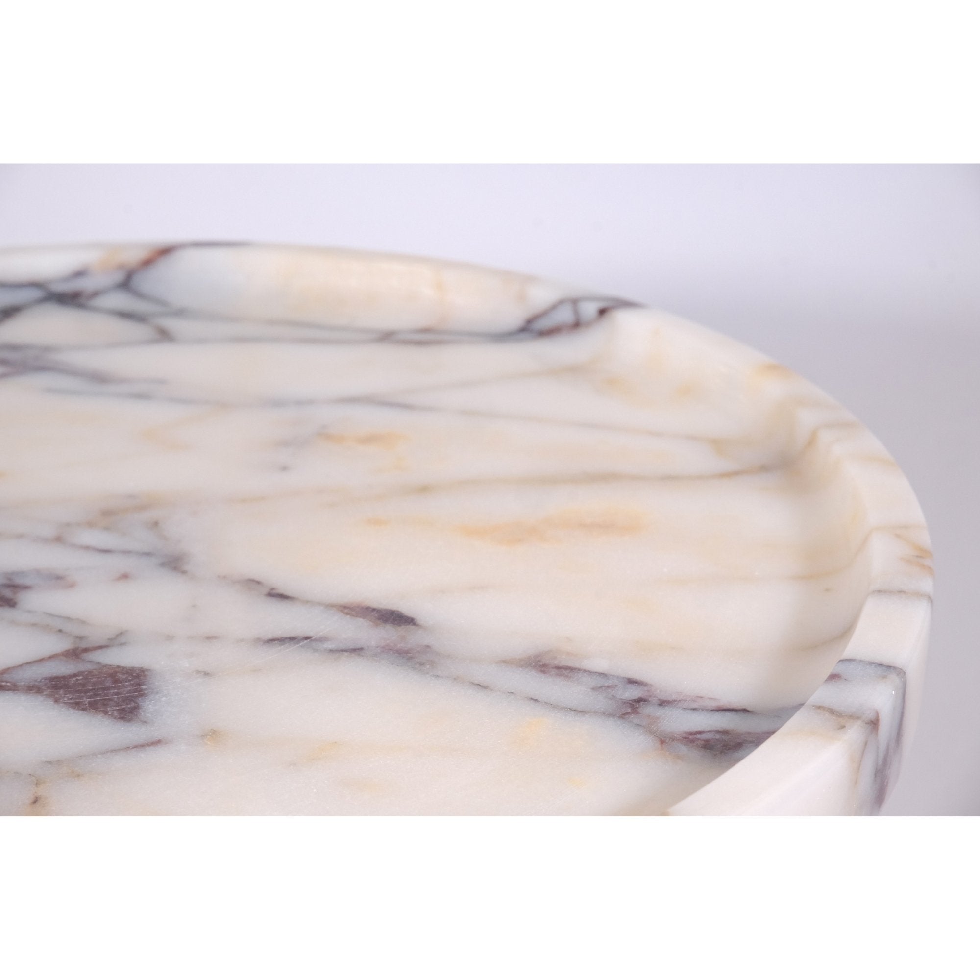 Close-up detail of polished Calacatta Viola marble texture and beveled rim on pedestal cake stand