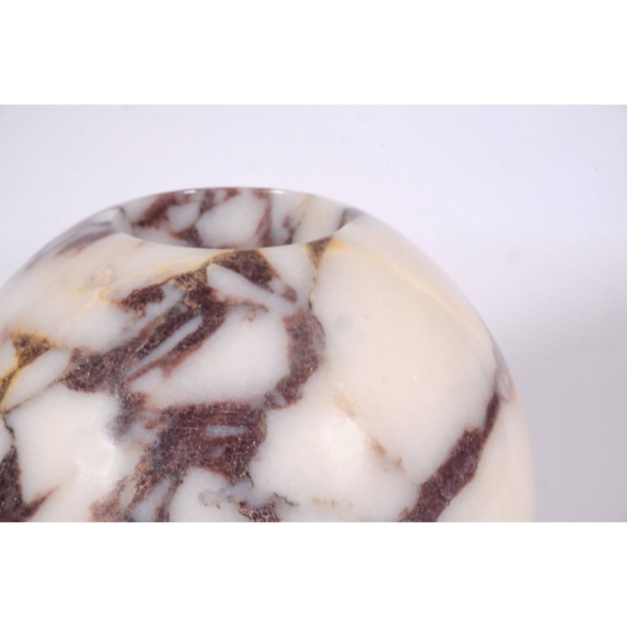 Close-up of Calacatta Viola marble vase surface, highlighting refined hand-polished finish and intricate natural stone patterns.