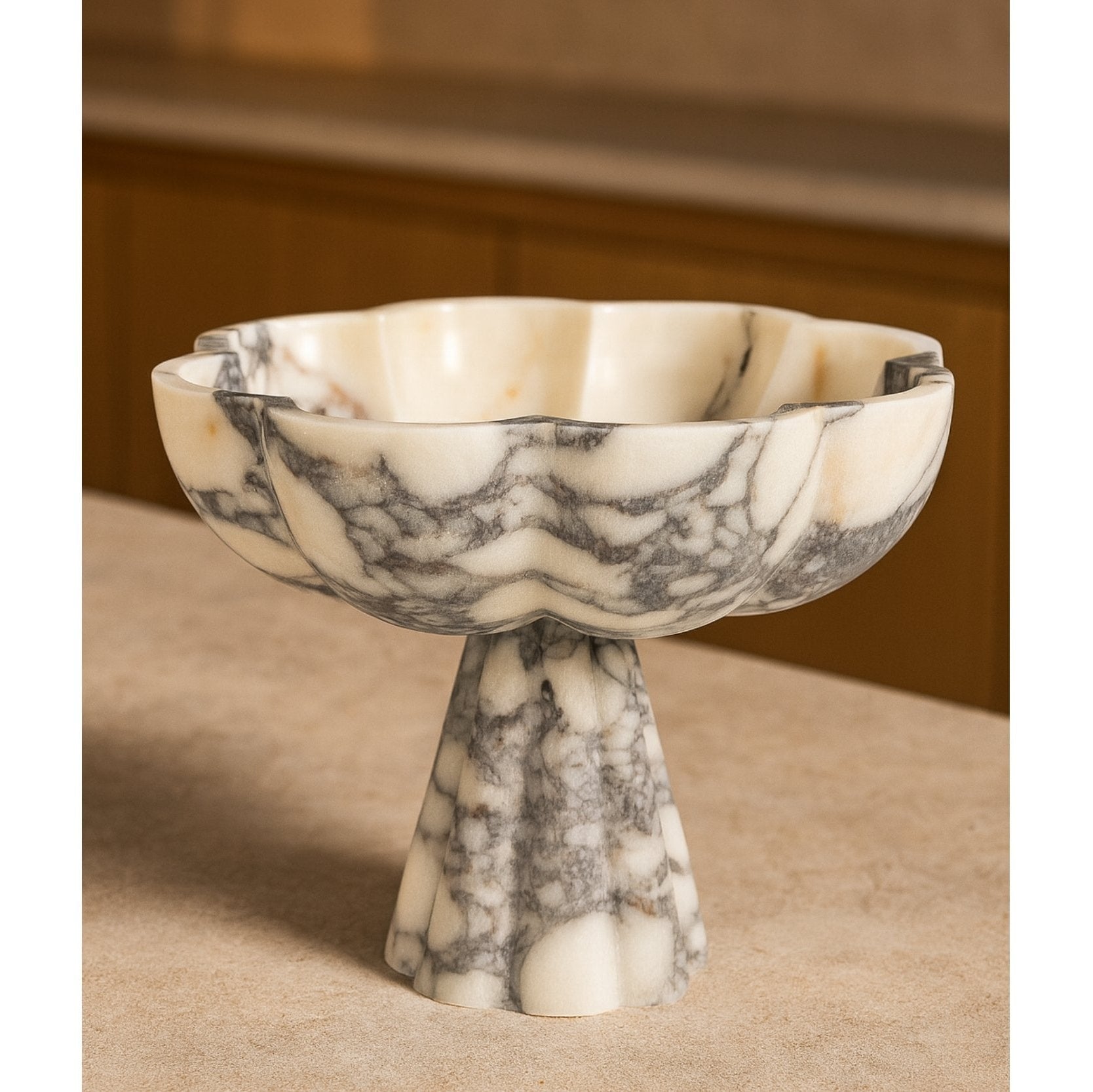 Hand-carved marble pedestal bowl on wooden tabletop, cozy home scene
