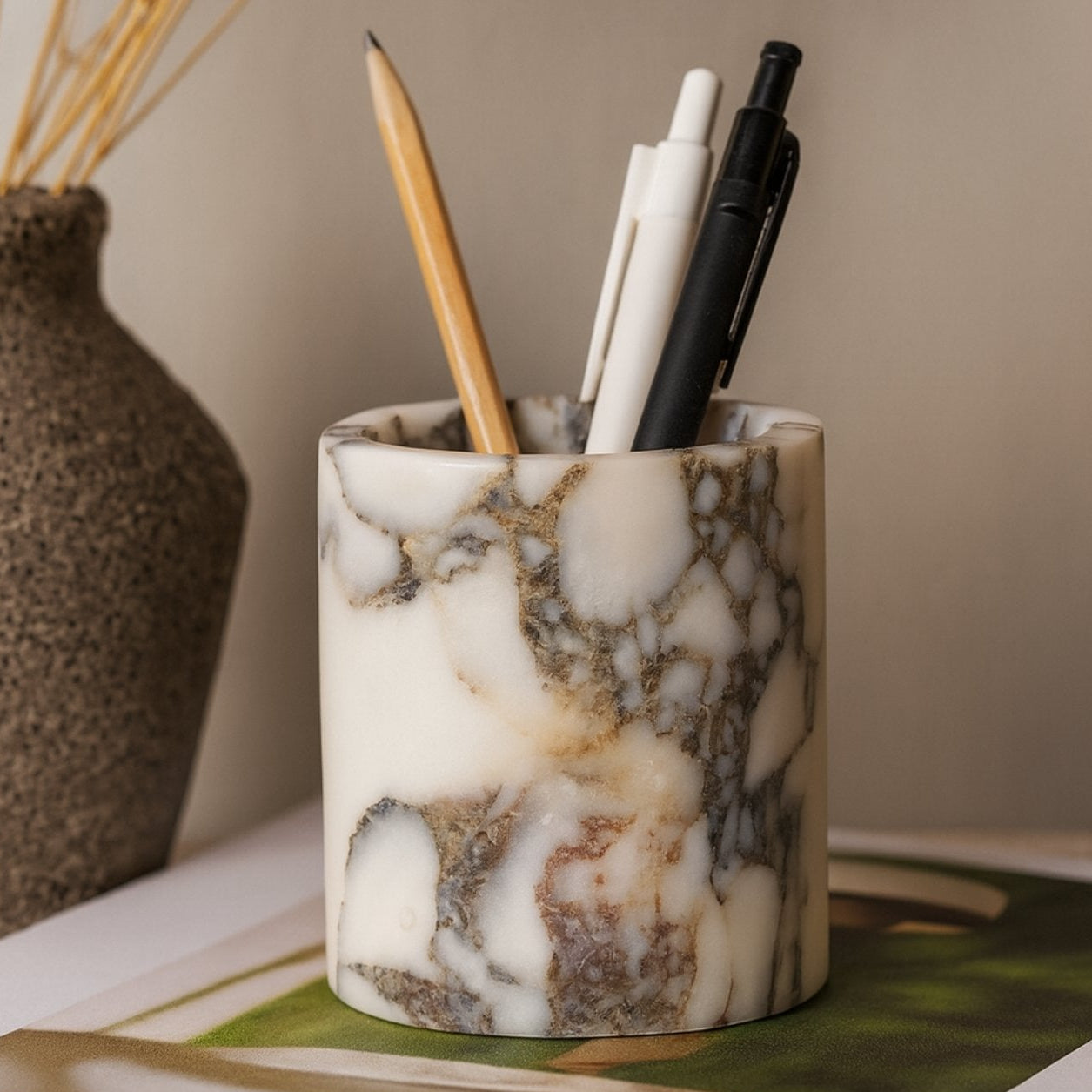 Calacatta Viola marble pen holder styled on a wooden desk with pens – warm lighting, modern rustic workspace aesthetic.