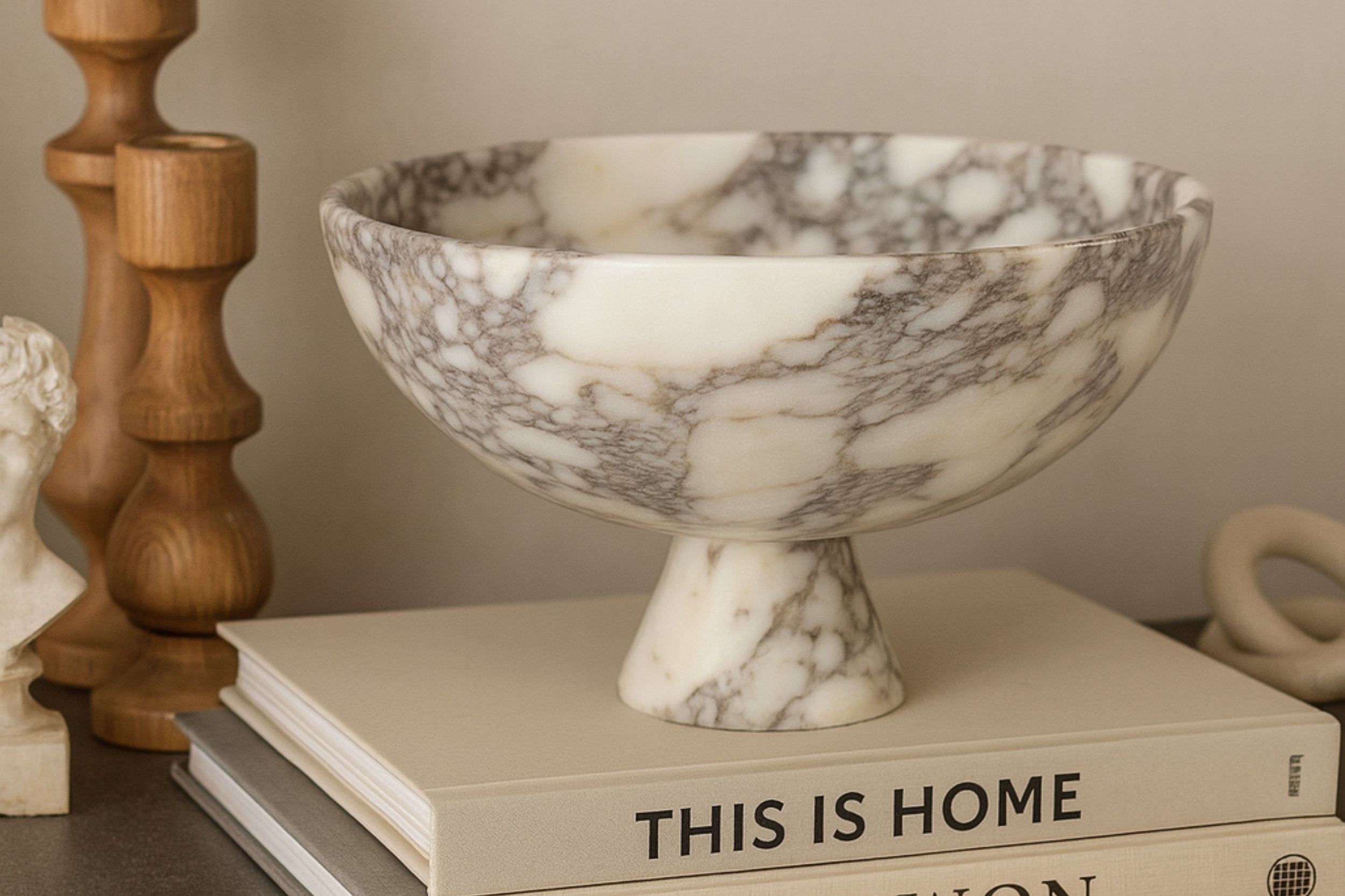 Calacatta Viola marble pedestal bowl styled on design books in a neutral living room – Petra Vera home decor.