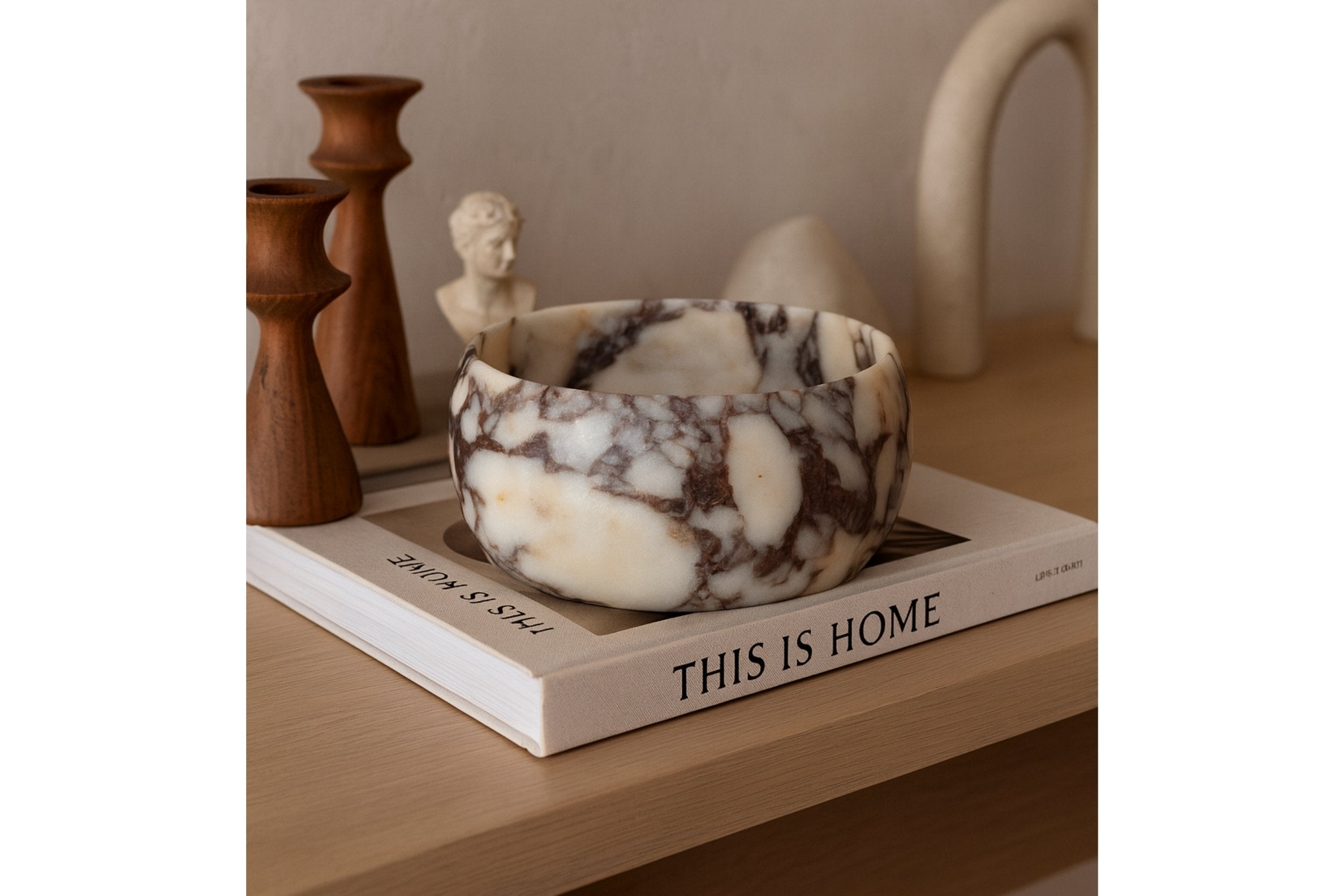 Hand-carved Calacatta Viola bowl on linen runner in warm natural light.