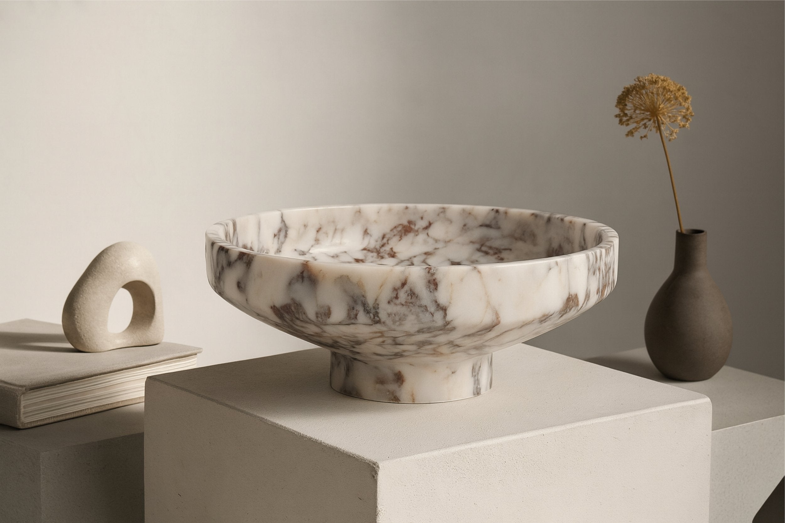 Marble pedestal bowl on wooden table with bread and linen, warm natural morning light scene.