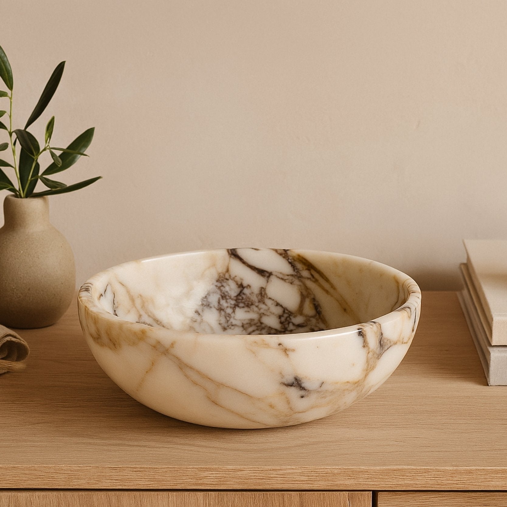 Handcrafted Calacatta Viola marble bowl displayed in a minimalist home setting beside decor accents, capturing warm natural tones and elegant ambiance.