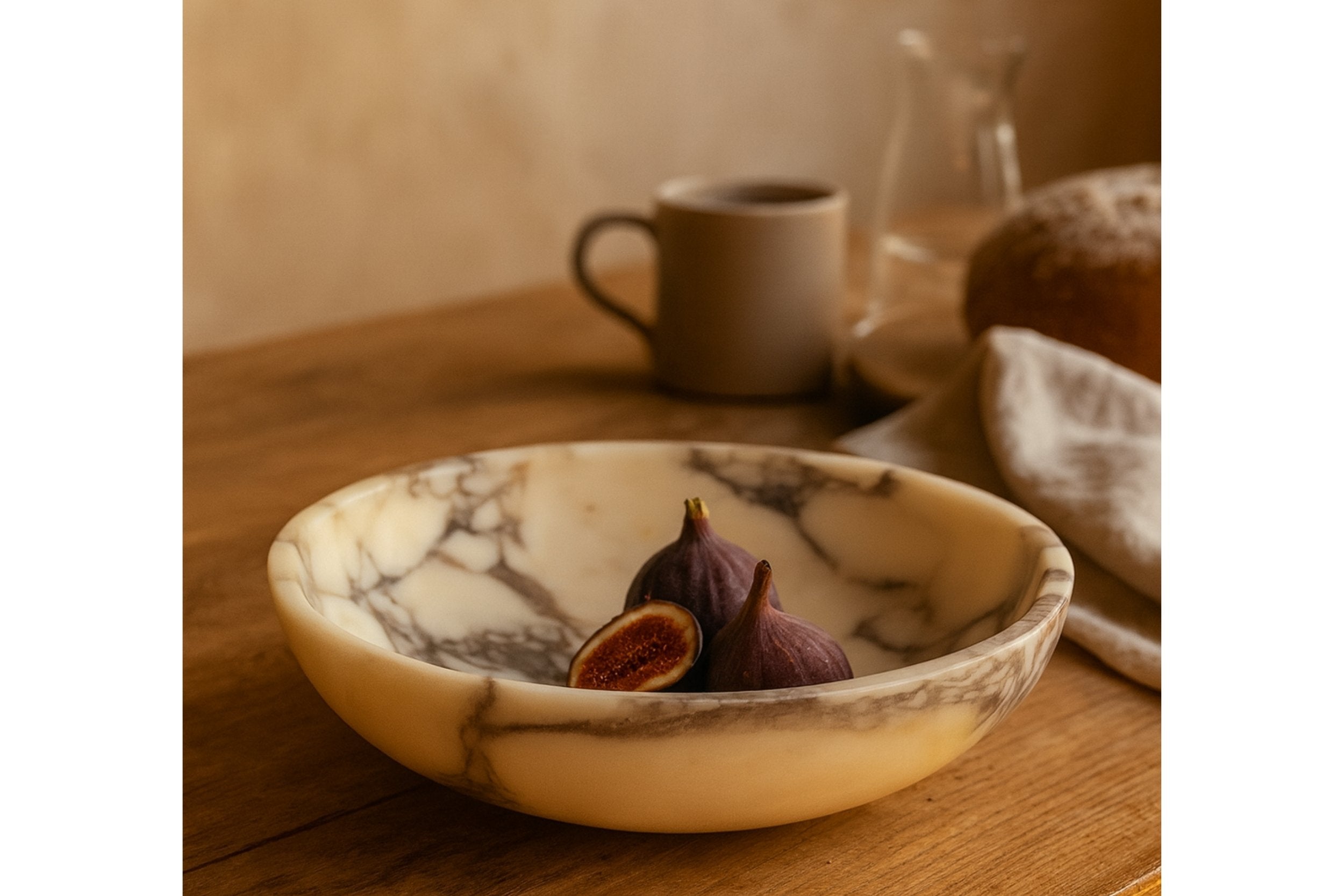 Calacatta Viola marble bowl with figs on wooden table in warm natural light, evoking cozy luxury and artisanal elegance.
