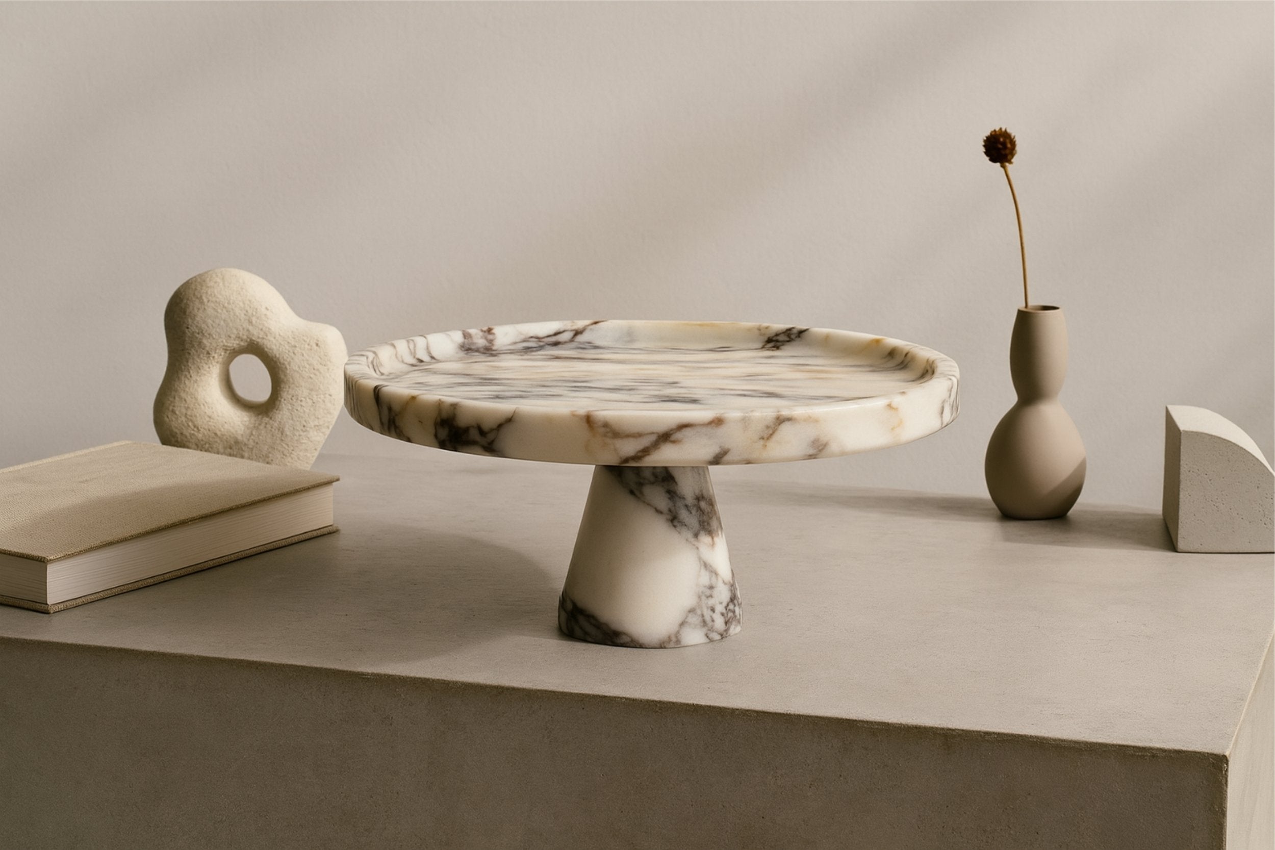 Designer shelf scene with marble pedestal cake stand used as table centerpiece for pastries and treats