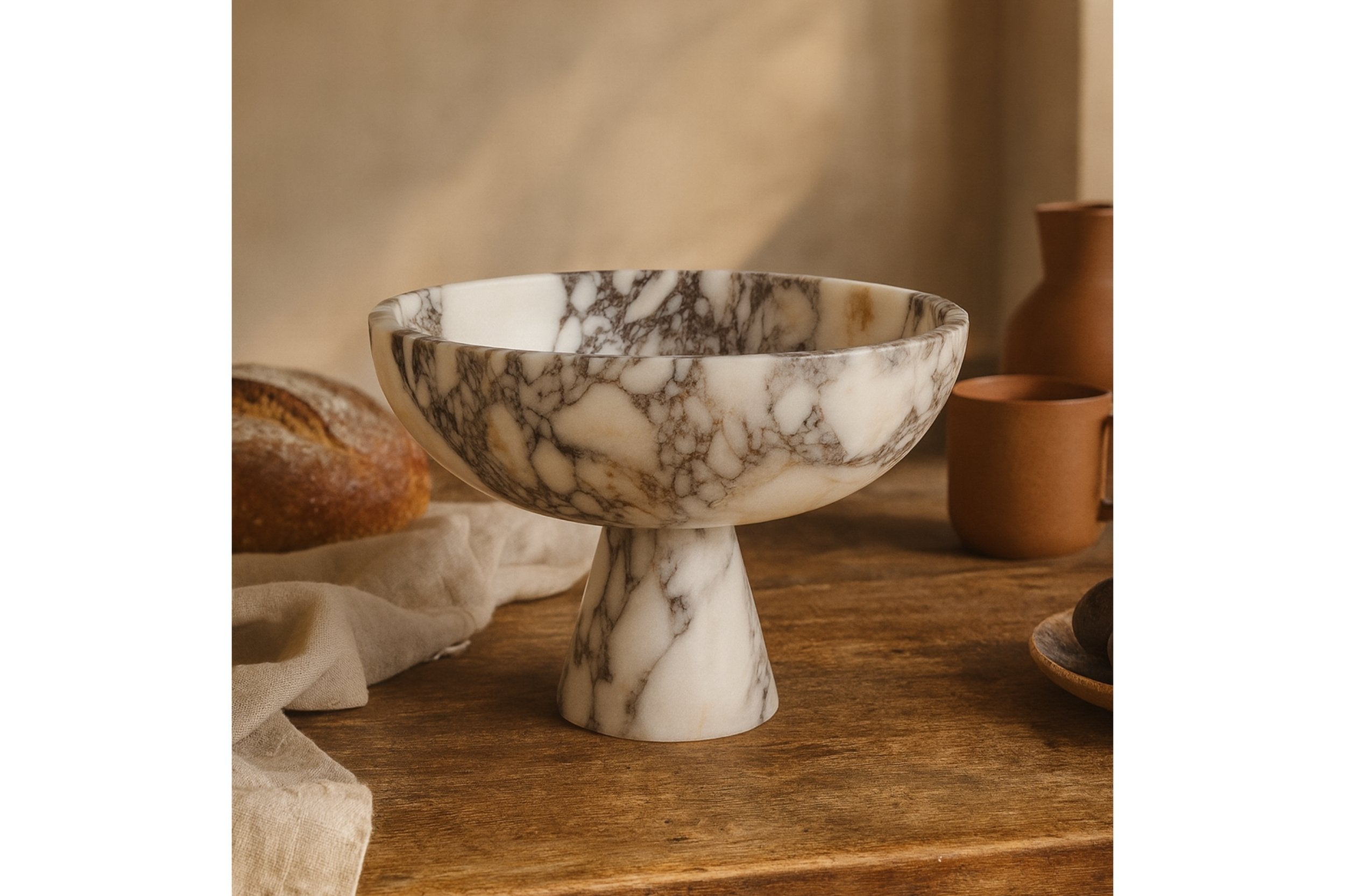 handmade calacatta viola marble footed bowl on wooden table with olive branch and warm earthy tones