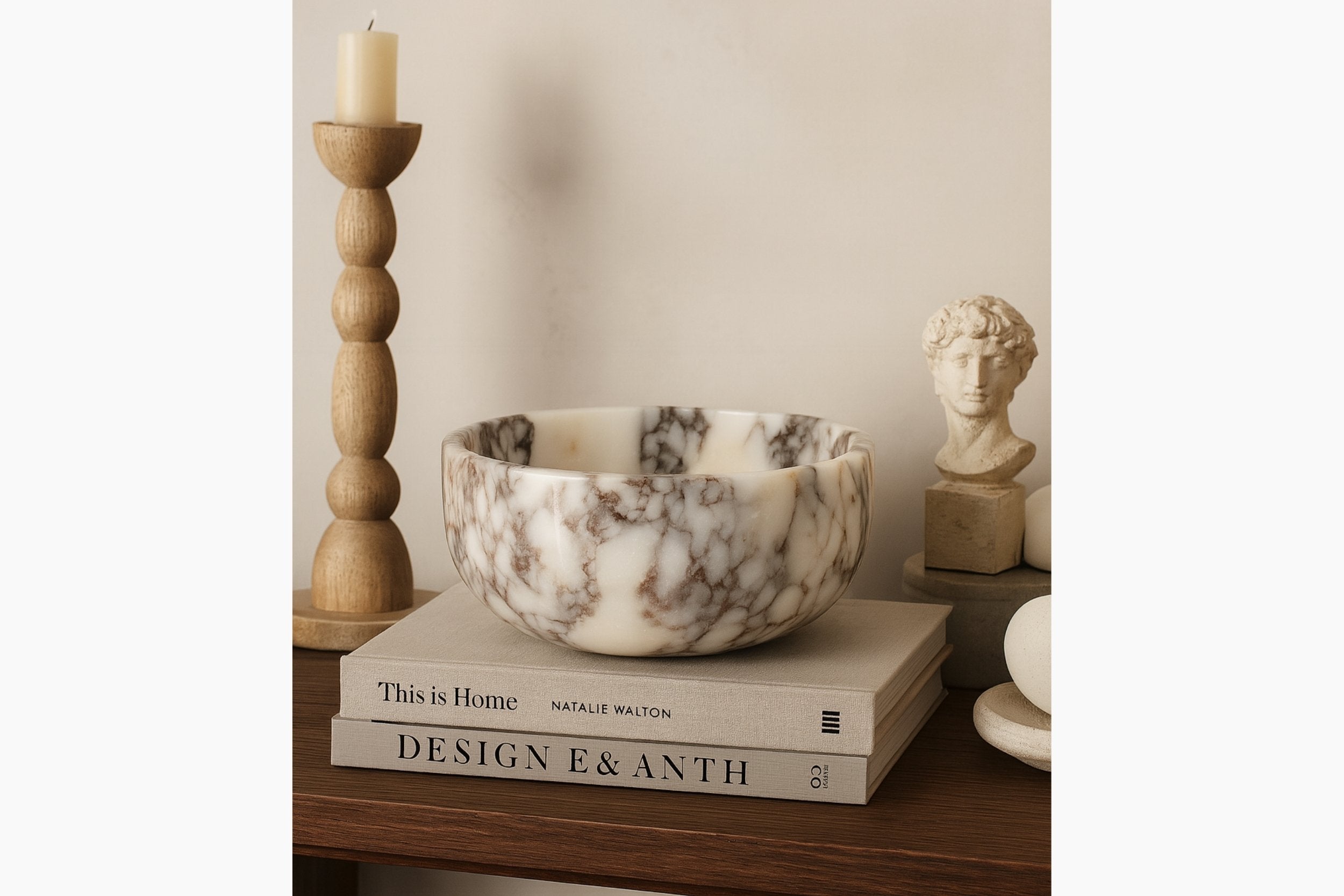 Calacatta Viola marble pedestal bowl displayed with designer books and sculptural decor in a neutral setting.