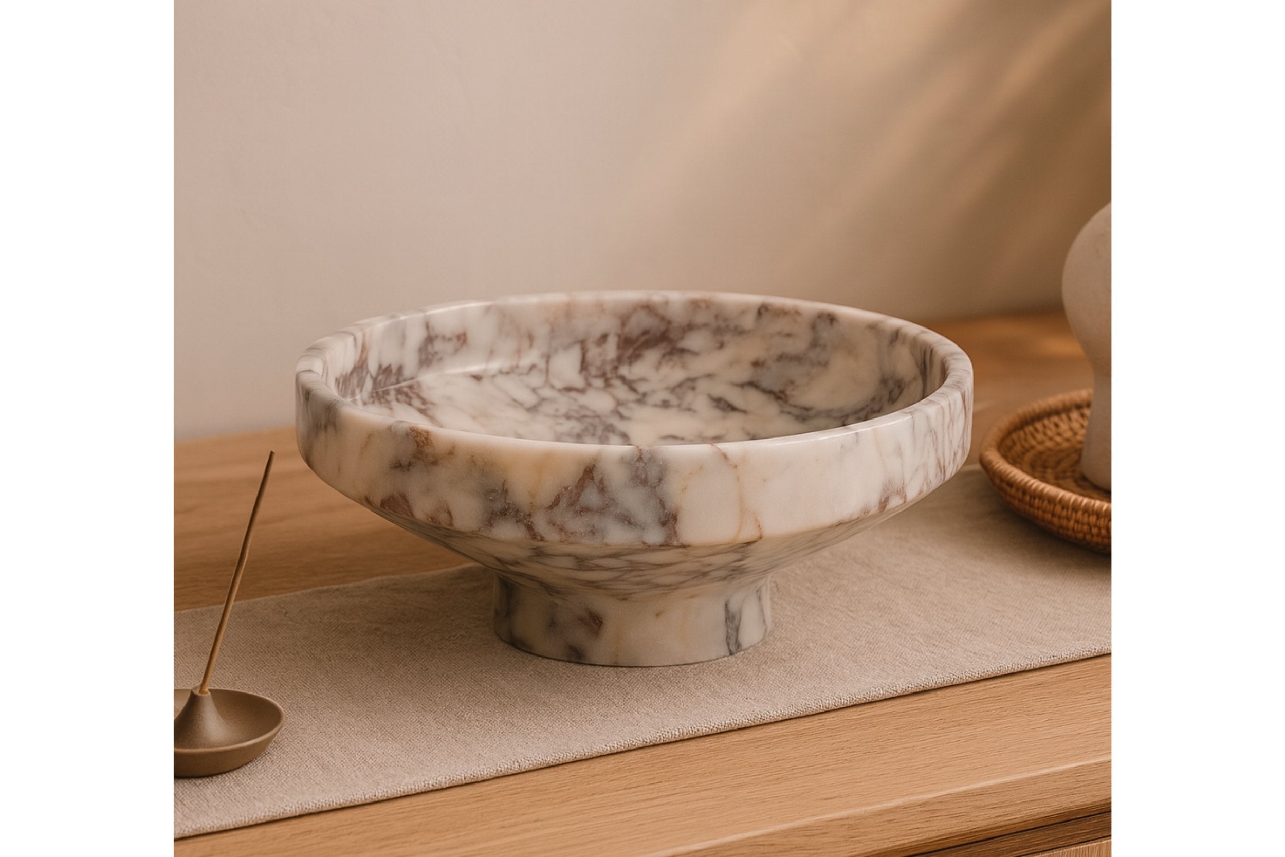 Hand-carved Calacatta Viola bowl displayed on console table with books and ceramic decor, Scandinavian styling.