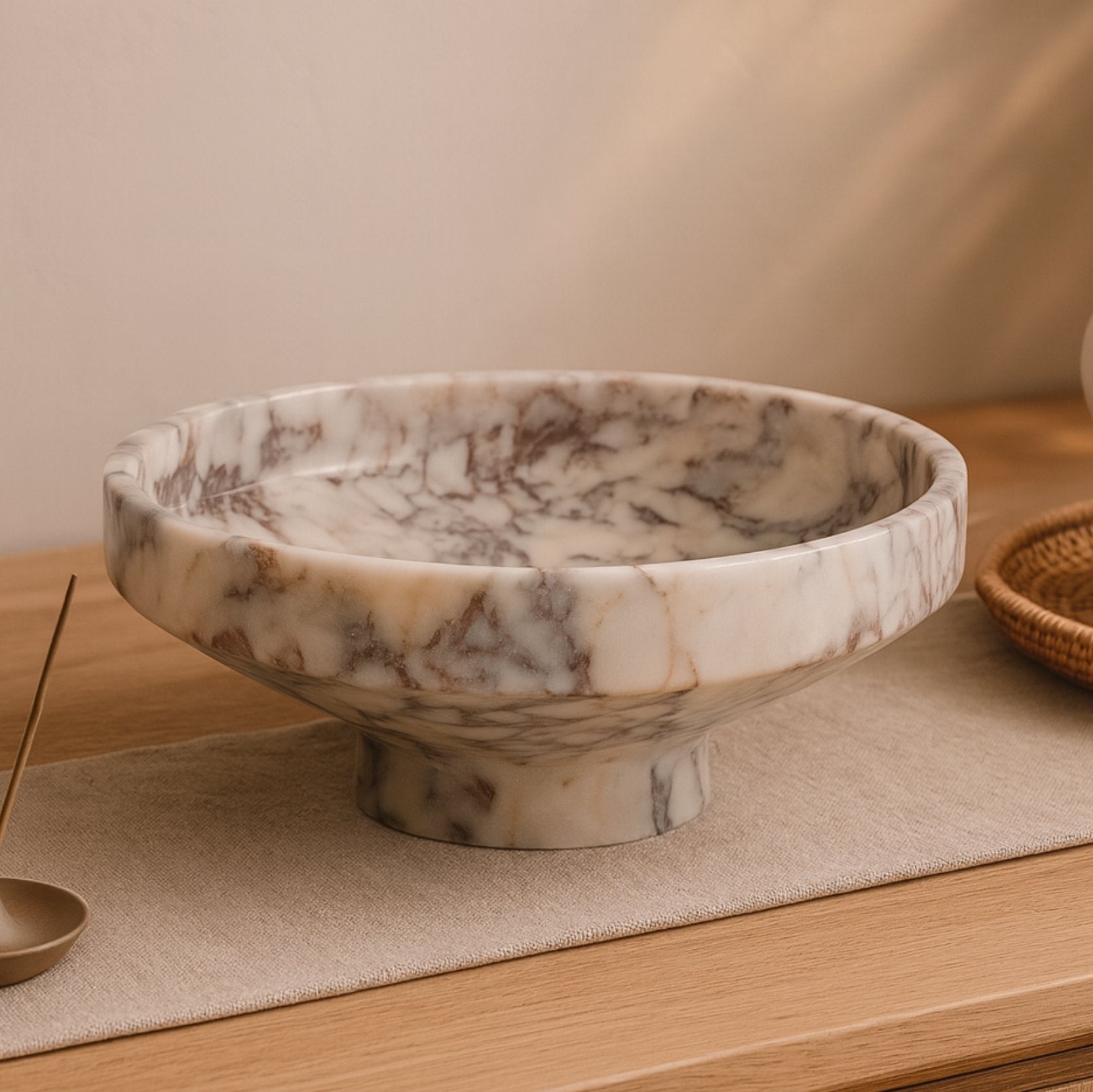 Hand-carved Calacatta Viola bowl displayed on console table with books and ceramic decor, Scandinavian styling.