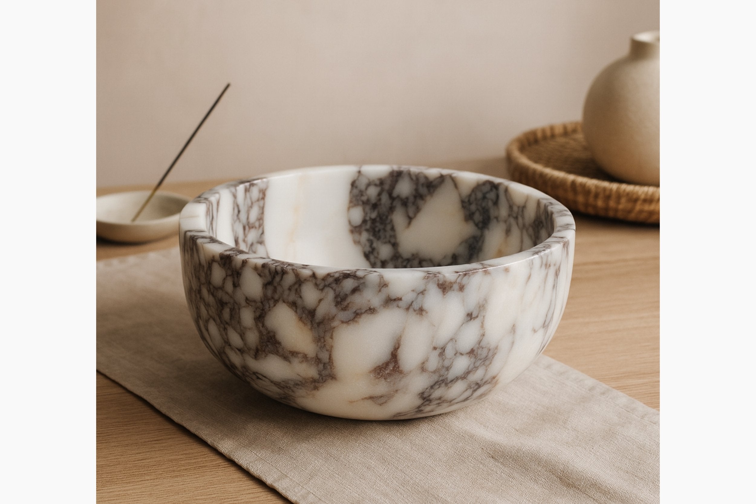 Calacatta Viola marble bowl placed on linen table with soft beige background and elegant vase decor.