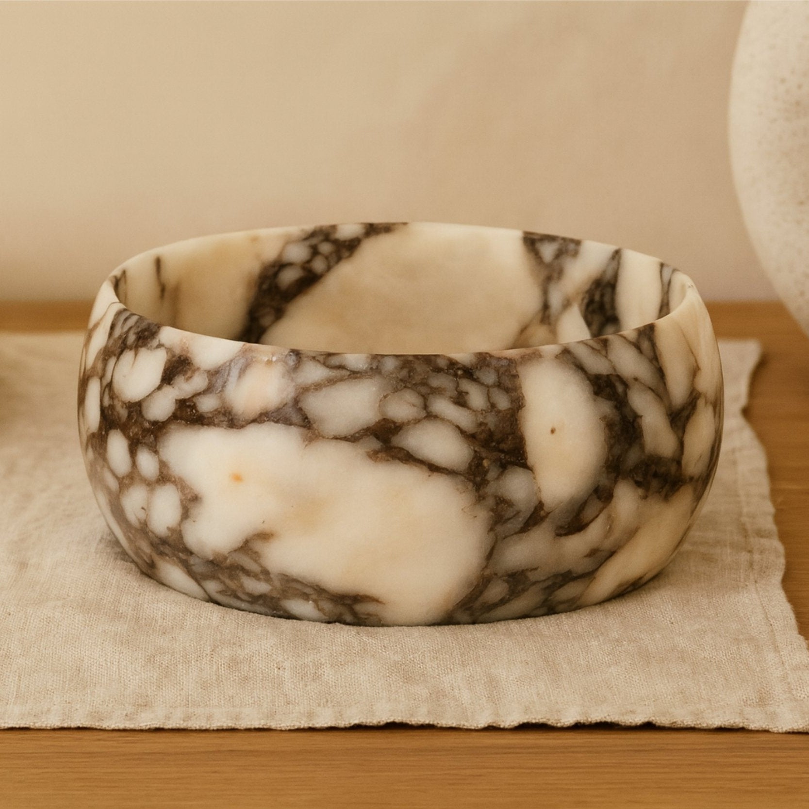 Calacatta Viola marble bowl displayed on design books in a calm interior.
