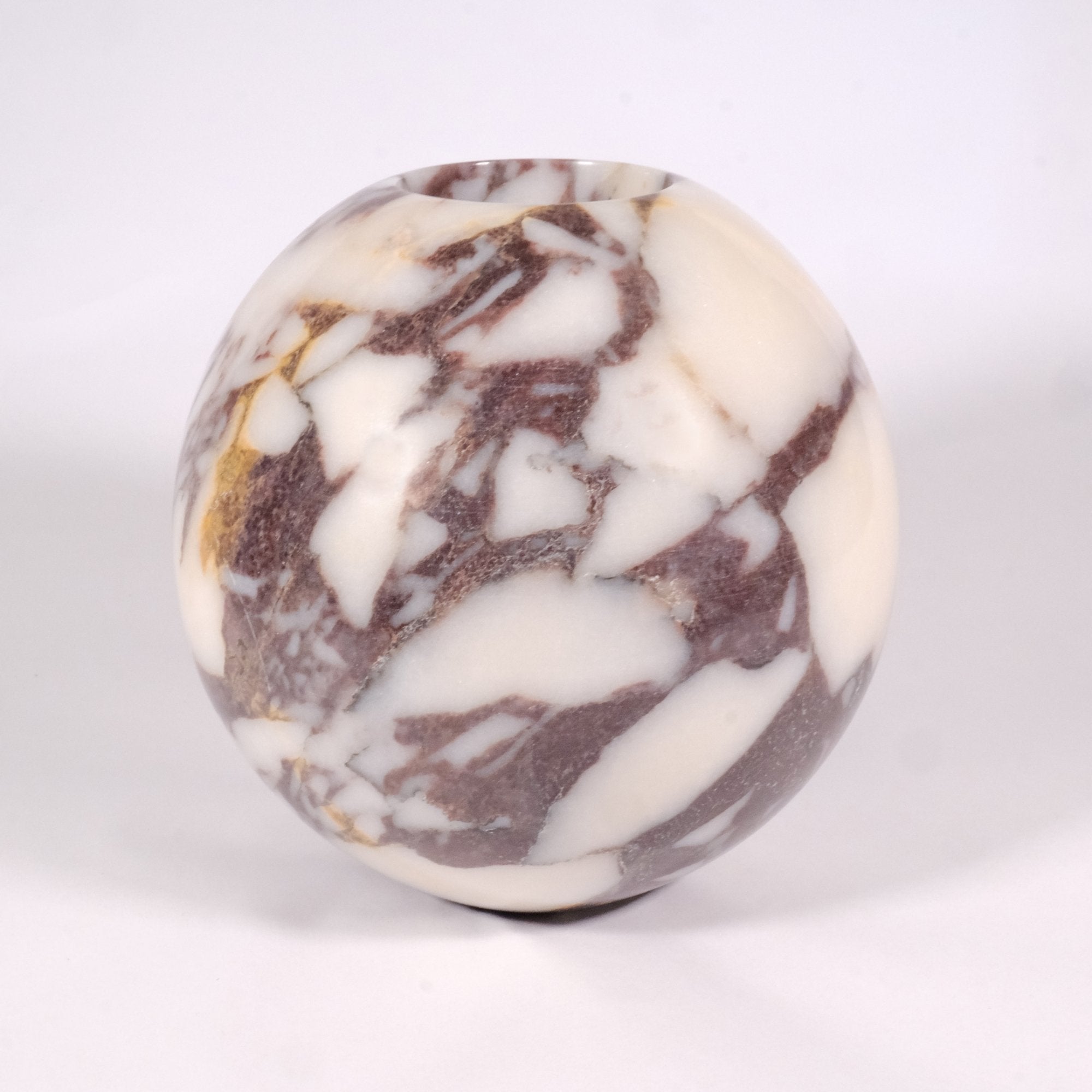 Top view of a spherical Calacatta Viola marble vase showcasing unique natural veining and polished marble texture.
