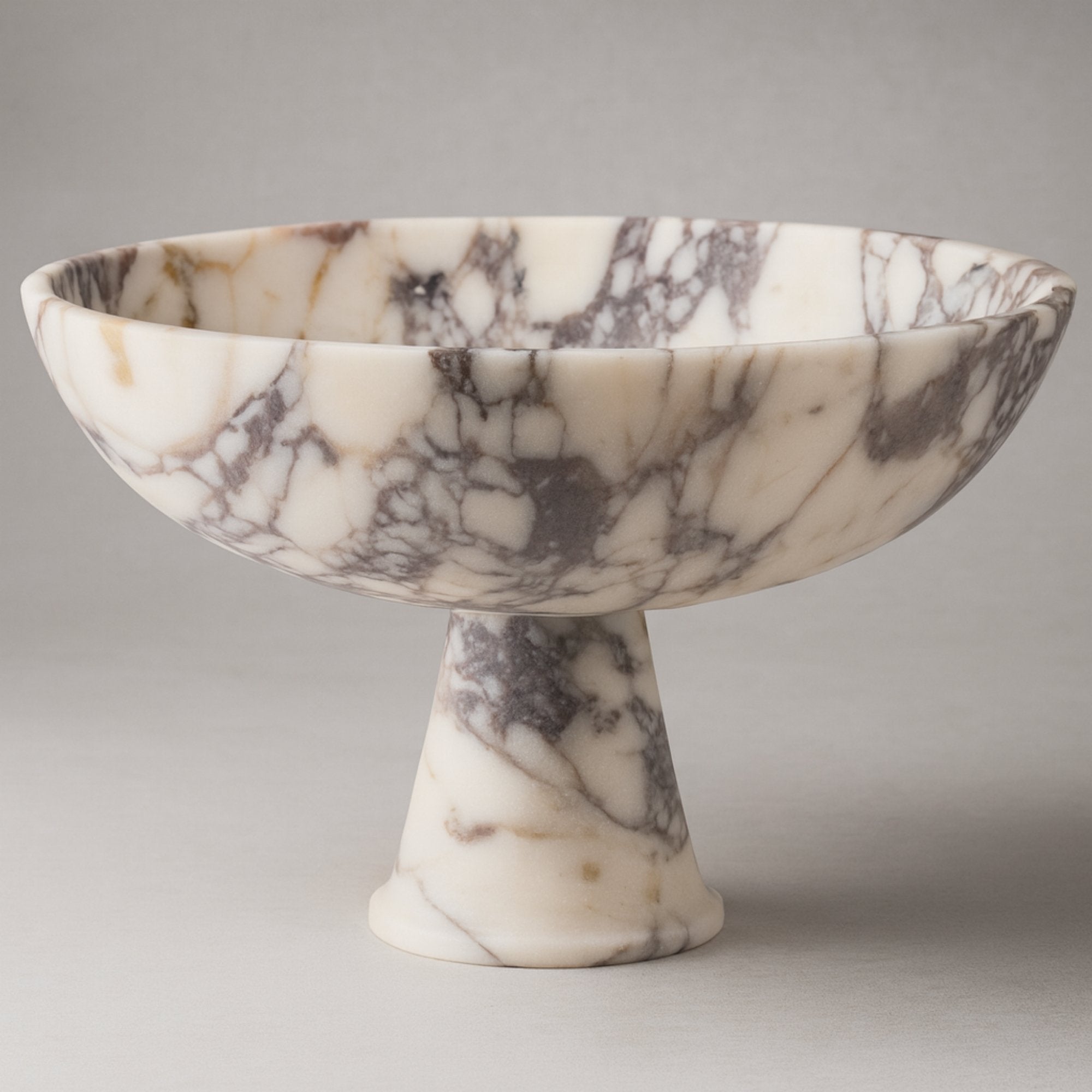 Calacatta Viola marble pedestal bowl with natural veining on soft neutral background.
