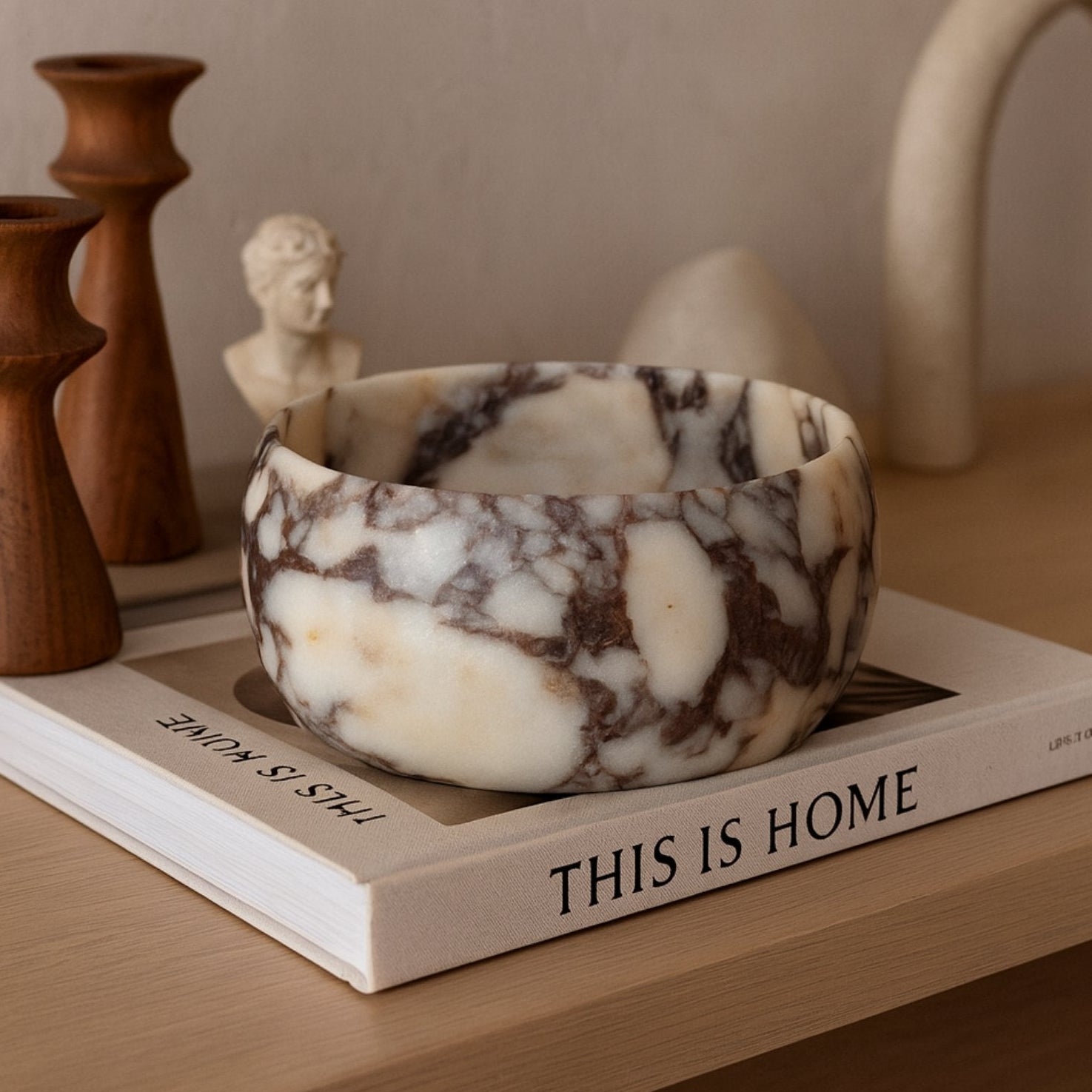 Hand-carved Calacatta Viola bowl on linen runner in warm natural light.