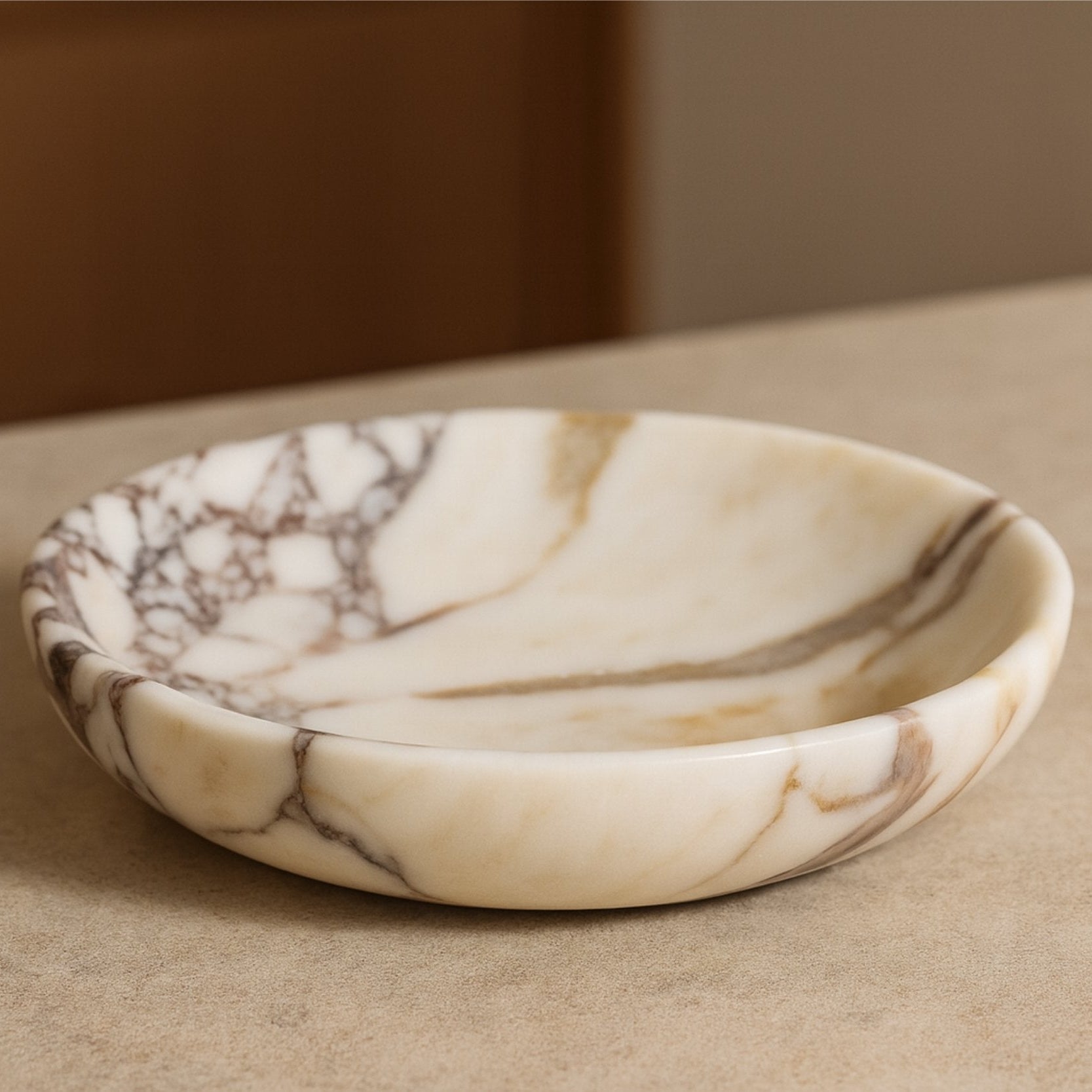 Elegant Calacatta Viola marble plate on a warm-toned surface with natural daylight, capturing the stone’s rich texture and tones.