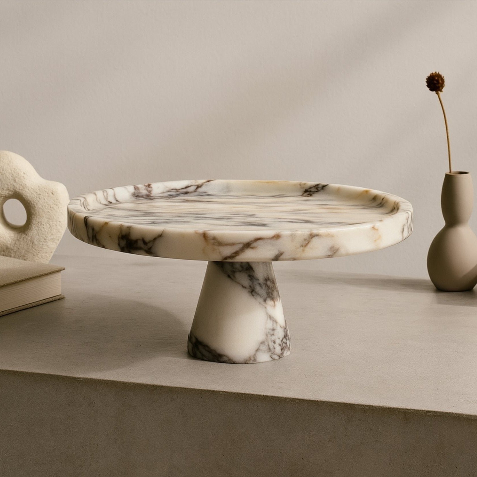 Designer shelf scene with marble pedestal cake stand used as table centerpiece for pastries and treats