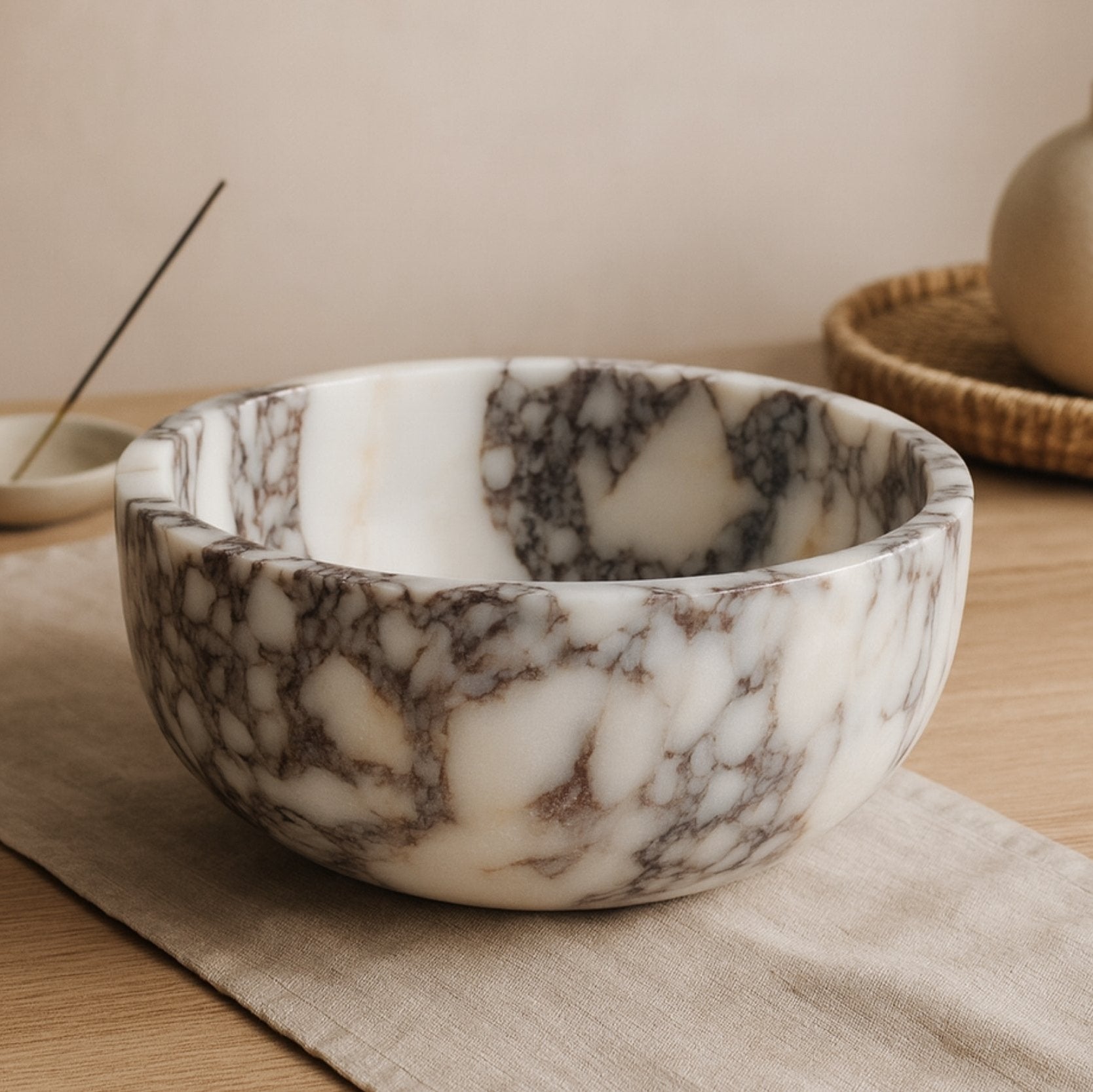 Calacatta Viola marble bowl placed on linen table with soft beige background and elegant vase decor.