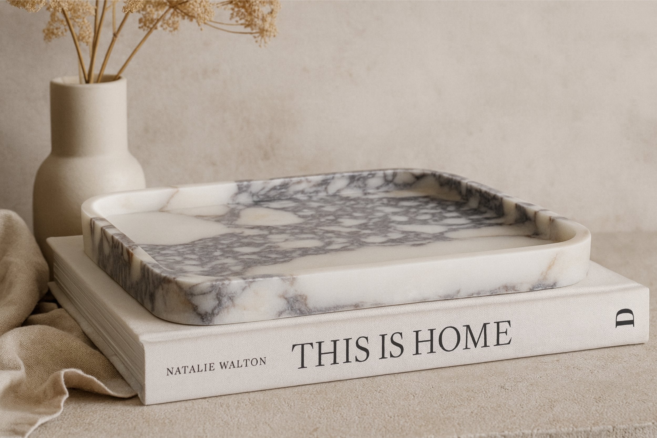 Calacatta Viola marble tray placed on a book titled This Is Home with beige decorative accents.