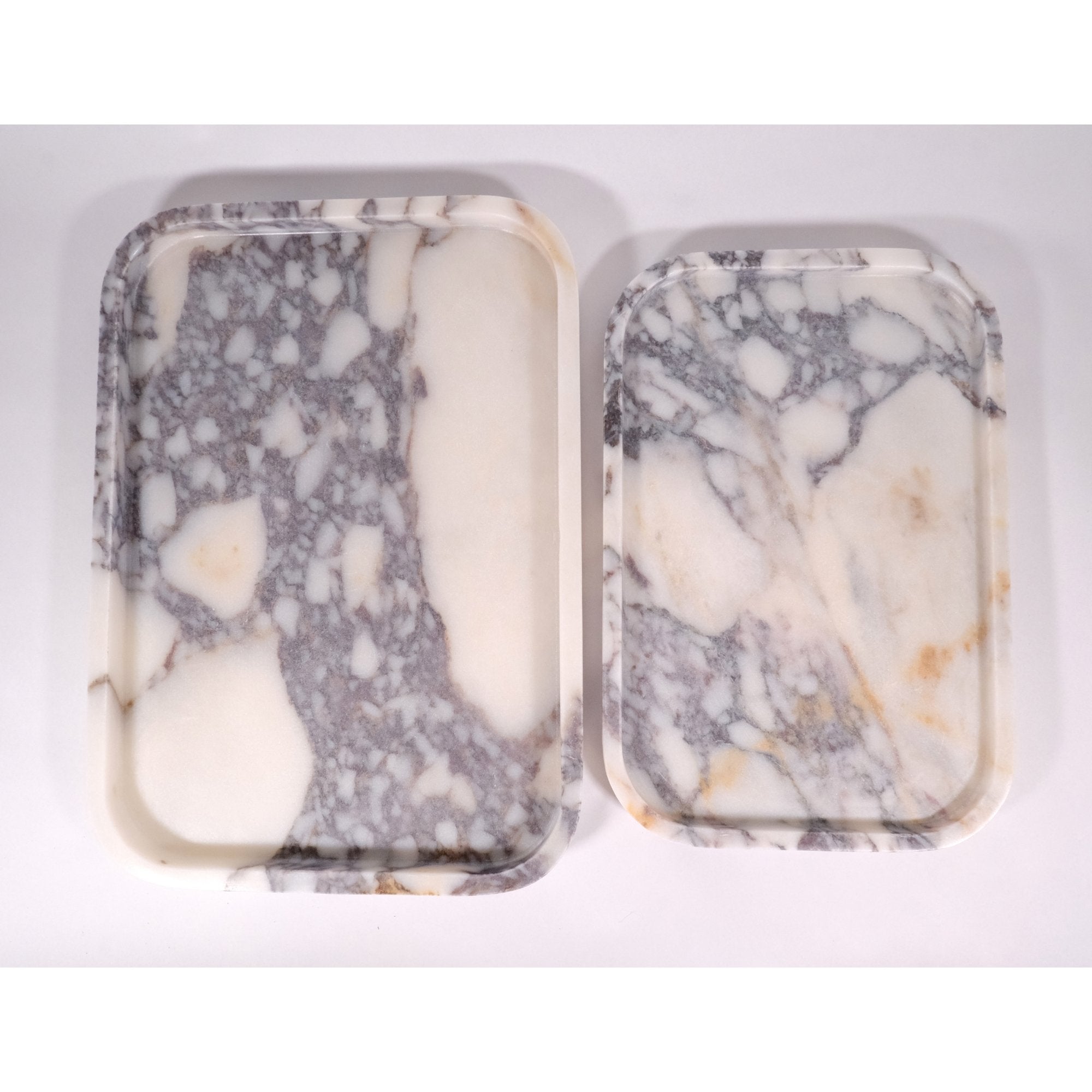 Top view of two Calacatta Viola marble trays showing natural veining and rounded edges.