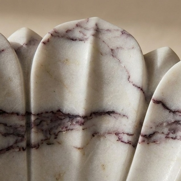 Close-up detail of hand carved marble flower sink highlighting petal texture and natural veining
