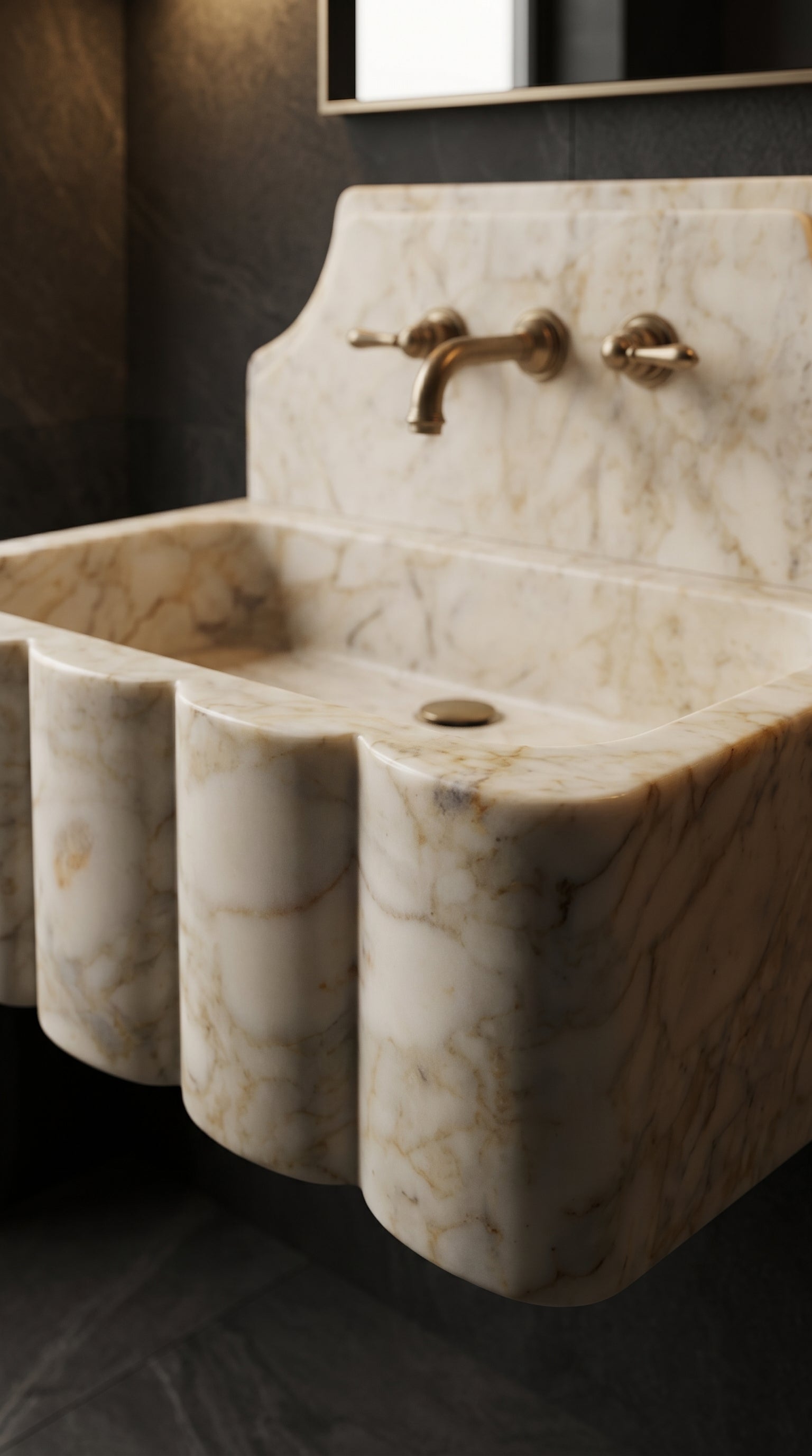 Close-up of a handcrafted Calacatta Gold marble wall-mounted sink with a scalloped front, integrated backsplash and brass faucet.