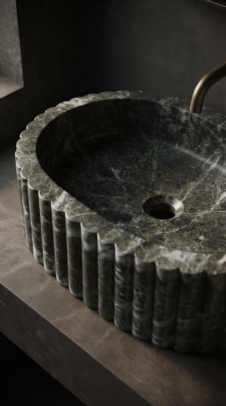 Angled close-up of a marble vessel sink showing its polished basin, open drain hole, rounded rim and vertically fluted exterior.