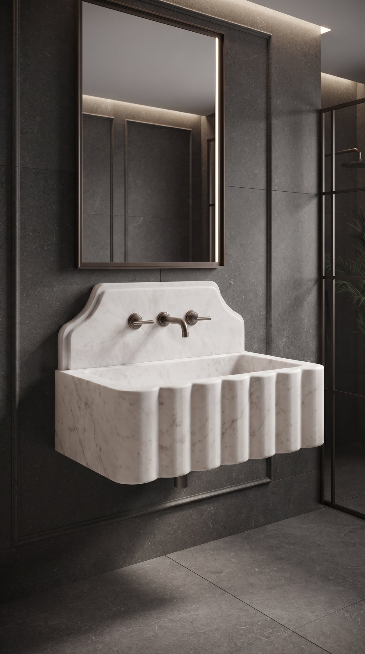 Handcrafted white marble wall mounted sink with sculptural scalloped front in a modern bathroom with dark natural stone walls.
