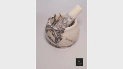 Handcrafted Calacatta Viola marble mortar and pestle in action, grinding herbs with smooth finish and durable marble weight.