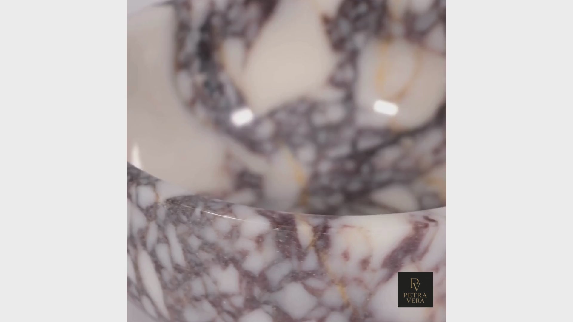 Rotating view of handcrafted Calacatta Viola marble bowl showing natural veining and refined stone texture under warm light.