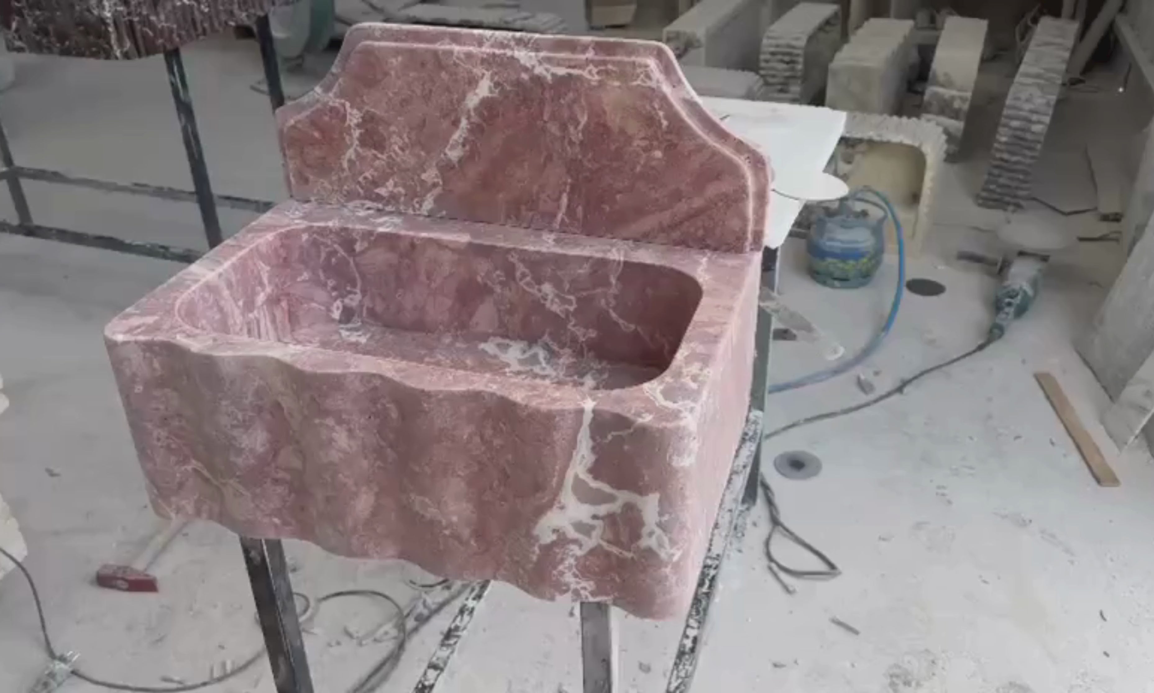 Red travertine wall mounted sink showcasing natural stone texture and handcrafted details.