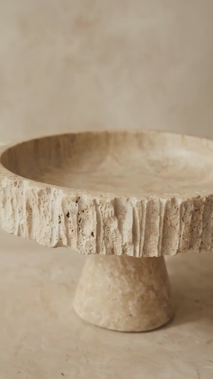 Travertine fluted pedestal bowl rotating in soft natural light