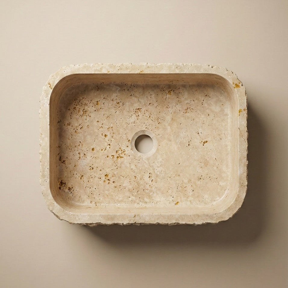Top view of rectangular travertine vessel sink showing natural stone texture and drain detail